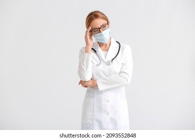 Portrait Of Sad Female Doctor Wearing Medical Mask On Light Background