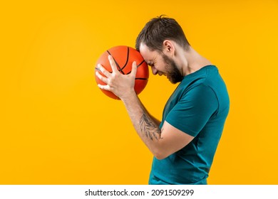 Portrait Of Sad Frustrated Fan Man Pressing Basketball Ball To His Head With Regret Dossapointed By Final Score Of The Play, He Lost His Money At Bookmaker's Betting At The Wrong Team.