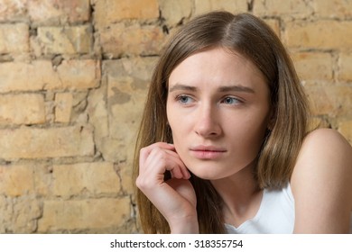 Portrait of a sad girl on a background of an old brick wall