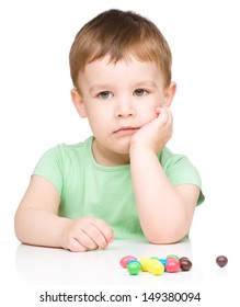 Portrait Of A Sad Little Boy With Colorful Candies, Isolated Over White