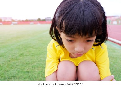 Portrait Of Sad Little Girl Sitting In The Stadium