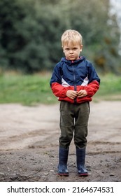 Portrait Of A Sad Lonely Boy In Bad Weather In Autumn. The End Of Summer Fun. Dirt And Humidity Outdoors There Is No Activity For Children.