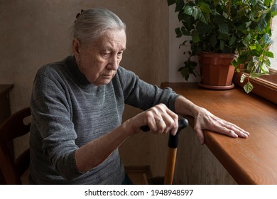 Portrait Of A Sad Lonely Old Woman, Sitting At Home By The Window. Old Age, Loneliness, Sadness, Hopelessness. 