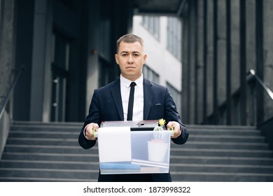 Portrait Sad Male Office Worker In Depression With Box Of Personal Stuff. Businessman Lost Job. Fired Man Outdoors. Depressed Jobless Person. Unemployment Concept. Left Without Money.