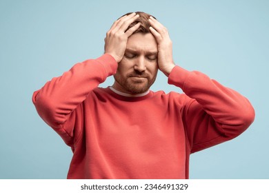 Portrait of sad man having life troubles holding head with suffering face on studio blue background. Frustrated, confused male with headache, life problems, midlife crisis. Stress, panic, desperation. - Powered by Shutterstock