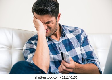 Portrait Of A Sad Man Holding Bank Card At Home