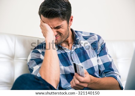 Portrait of a sad man holding bank card at home