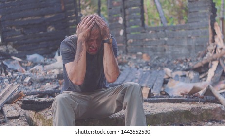 Portrait Of A Sad Man On The Background Of A Burned House, After Fire Or Artillery Attack. Consequences Of Fire Disaster Accident. Ruins After Fire Disaster, Loss And Despair Concept.