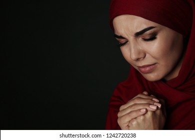 Portrait Of Sad Muslim Woman In Hijab  Praying On Dark Background. Space For Text