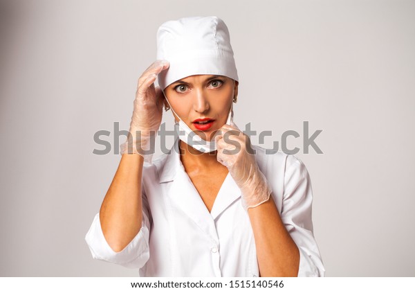 Portrait of a sad nurse in a white suit isolated on gray background