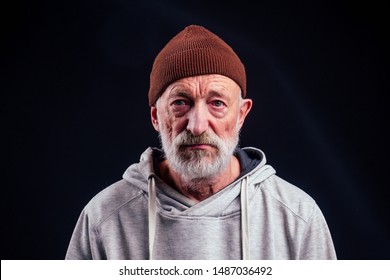 portrait of sad old senior male tramp wearing warm brown hat and leaky gloves,holding metal canned bank jar for money alms in studio black background. - Shutterstock ID 1487036492
