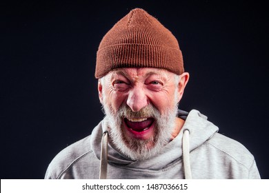 portrait of sad old senior male tramp wearing warm brown hat and leaky gloves,holding metal canned bank jar for money alms in studio black background.