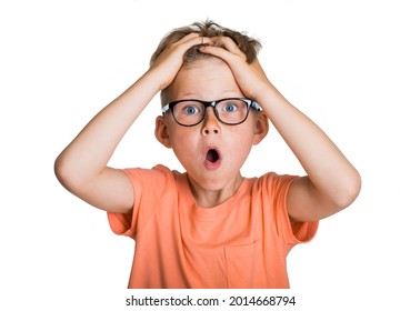 Portrait of sad school boy and time to go to school. Upset terrified kid boy holding touching head with hands. Child in glasses looking at camera. Surprised pupil with big eyes and open mouth