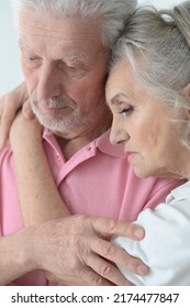 Portrait Of Sad Senior Couple Hugging At Home