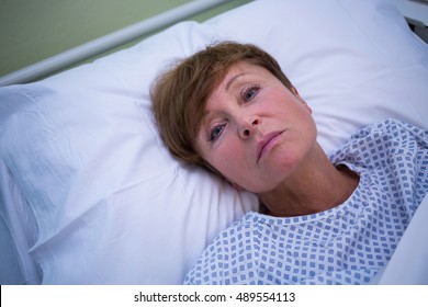 Portrait Of Sad Senior Patient Lying On A Bed In Hospital Room