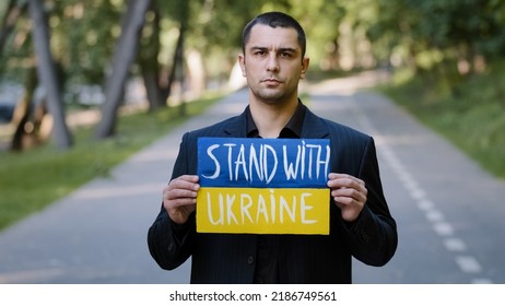 Portrait Sad Serious Man Activist Patriot Guy Stand Outdoors Hold Cardboard With Written Inscription Stand With Ukraine Protests Against Military Conflict Demonstrate Opposition Anti Violence Banner