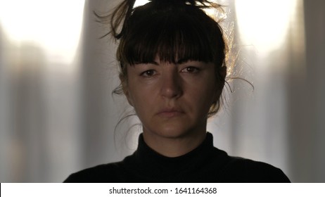 portrait of sad tortured woman with tousled hair looking at camera 