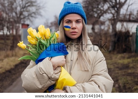 Portrait of sad Ukrainian woman holding tulip flowers with Ukrainian flag. War between Russia and Ukraine. Сток-фото © 