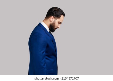 Portrait of sad upset bearded man standing with his head down and looking, having with dissatisfied sadness face, wearing official style suit. Indoor studio shot isolated on gray background. - Powered by Shutterstock