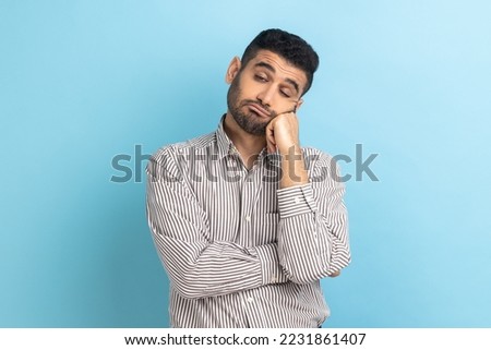 Portrait of sad upset or bored bearded businessman standing and looking at camera with dissatisfied sadness face, wearing striped shirt. Indoor studio shot isolated on blue background. Сток-фото © 