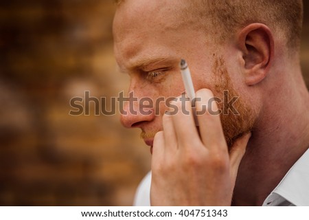 portrait of sad young bearded red hair man with sigaret  horizontal