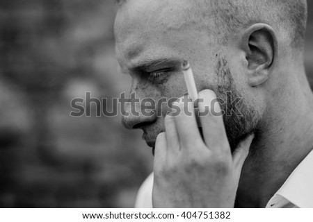 portrait of sad young bearded red hair man with sigaret black and white horizontal