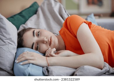 Portrait of sad young woman lying on bed in morning struggling with depression - Powered by Shutterstock