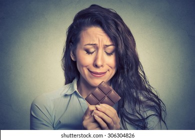Portrait sad young woman tired of diet restrictions craving sweets chocolate isolated on gray wall background. Human face expression emotion. Nutrition concept. Feelings of guilt 