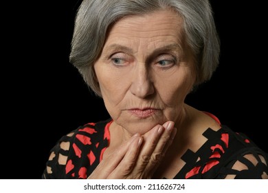 Portrait Of Saddest Older Woman In Red On A Black Background
