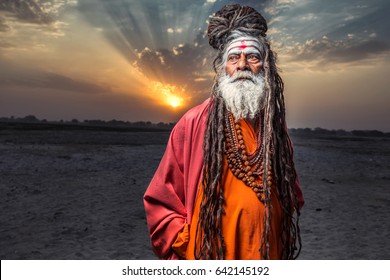 Portrait of sadhu standing with sunrise behind him, Varanasi, India.
