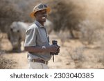 Portrait, safari and wildlife with a man ranger outdoor in a game park for nature conservation. Animals, binoculars and blurred background with an african male person on patrol in the wilderness