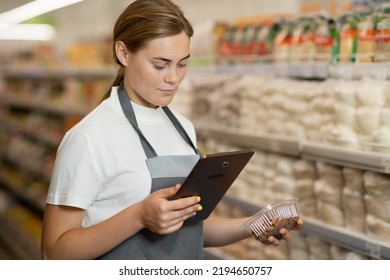 Portrait of a sales clerk wearing apron using a digital tablet with store shelves on background. copy space - Powered by Shutterstock