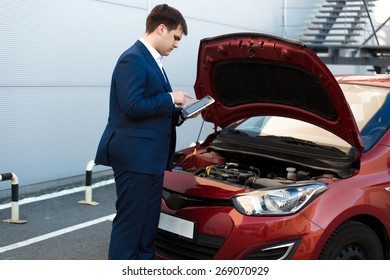 Portrait Of Sales Manager Making Photo Under Car Bonnet