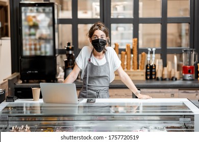 Portrait Of A Saleswoman Or Small Business Owner Wearing Medical Mask At The Counter In Cafe Or Small Shop. Concept Of A Retail Business During A Pandemic