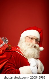 Portrait of Santa Claus carrying sack with gifts and looking at camera