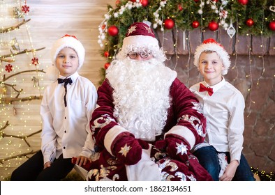 Portrait of Santa Claus with two boys, brothers in Santa hats, Christmas and New Year, children stayed at home.
