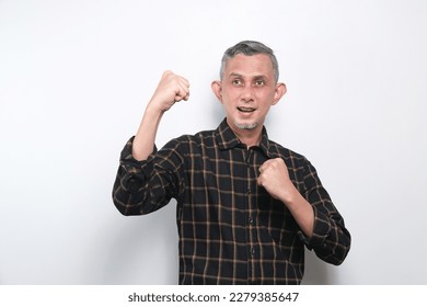 Portrait of a satisfied Asian man with casual shirt celebrating success isolated over white background.
 - Shutterstock ID 2279385647