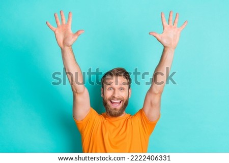 Portrait of satisfied carefree impressed guy blond hairdo wear orange t-shirt raise palms up shout yes isolated on teal color background