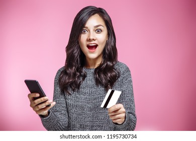 Portrait of a satisfied casual girl holding mobile phone and showing credit card isolated over pink background. - Shutterstock ID 1195730734