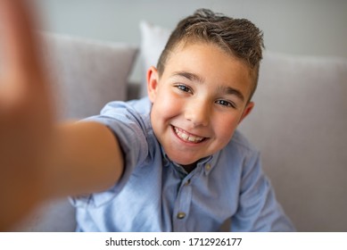 Portrait Of A Satisfied Cheerful Little Boy Holding Mobile Phone And Making Selfie. Funny Small Boy Taking Selfies And Grimacing. Smiling Cute Boy Taking Photos And Facetime Chatting.