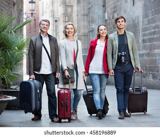 Portrait Of Satisfied Cheerful Young And Mature Couple With Baggage Outside In Spring