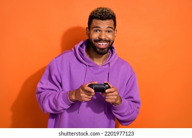 Portrait Of Satisfied Glad Man Hold Controller Use Playstation Toothy Smile Isolated On Orange Color Background