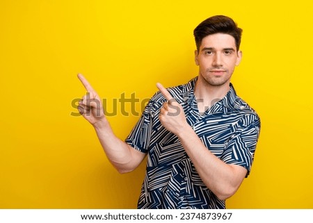 Portrait of satisfied guy with brunet hair bristle wear print shirt indicating at benefit empty space isolated on yellow color background