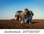 Portrait of satisfied mature farmer standing in field with tablet supervises the cultivation of soil.	