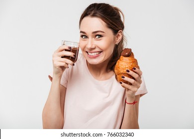 Portrait Of A Satisfied Pretty Girl Eating Croissant And Chocolate Pudding From A Glass Isolated Over White Background