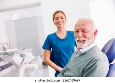 Portrait of satisfied senior male patient sitting at dental chair at dentist office smiling with doctor in the background - Powered by Shutterstock