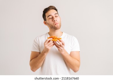 Portrait of satisfied young man with enjoying eating delicious slice of pizza, with closed eyes from pleasure on white isolated background. Studio shot of hungry male student eating tasty food. - Shutterstock ID 2118167660