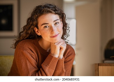 Portrait of satisfied young woman relaxing at home. Successful woman with hand on chin smiling and looking at camera. Beautiful natural girl stay at home with a serene expression.