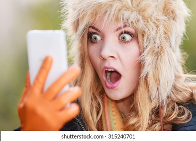 Portrait of scared afraid pretty woman talking on mobile phone. Gorgeous young girl in fur winter hat and jacket. Autumn fashion and communication. - Powered by Shutterstock