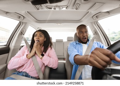 Portrait Of Scared African American Young Guy Driving Car On High Speed And Survived An Accident. Black Lady Gasping, Looking At Crash Or Animal On The Road, Windshield View. Oops, Shock Reaction.